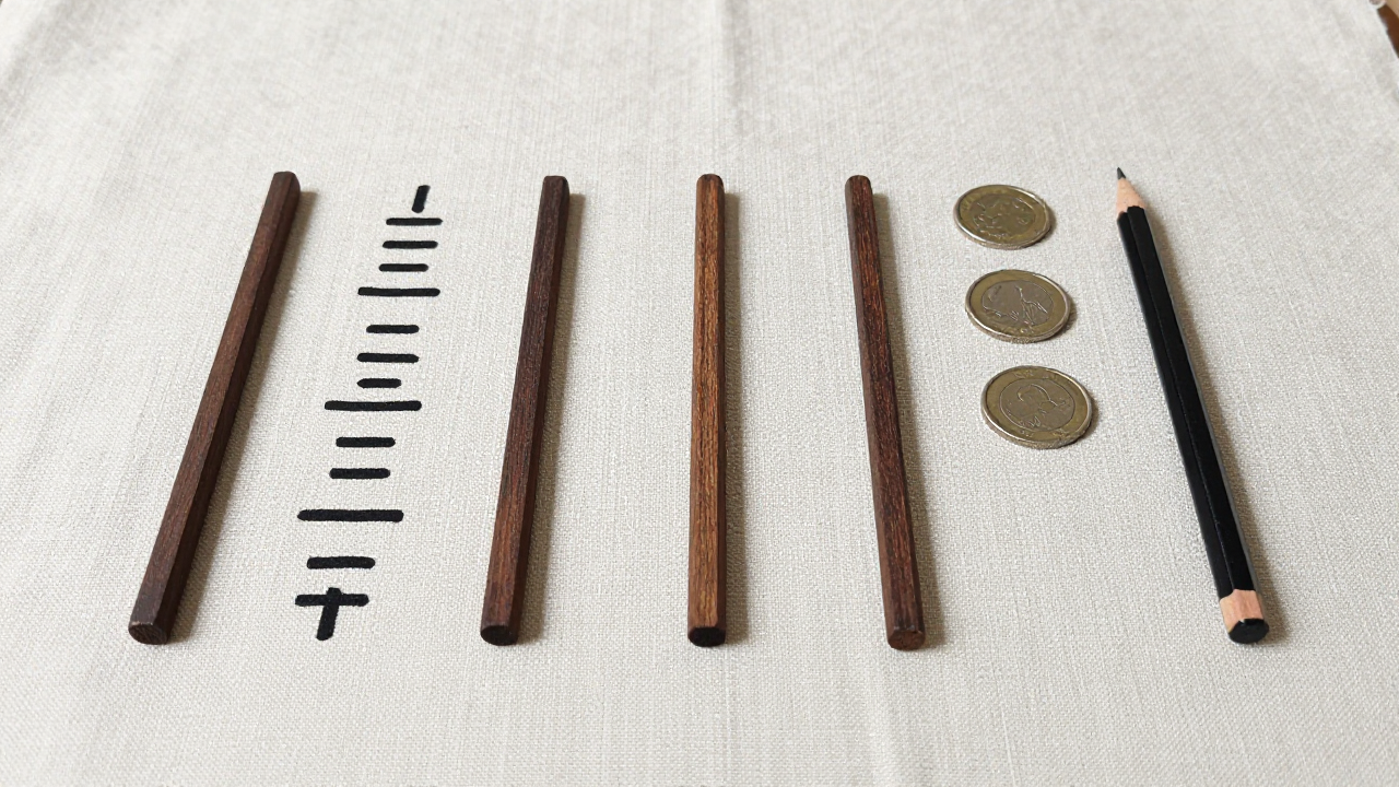 Six wooden line marks on blank linen cloth beside three coins and a pencil